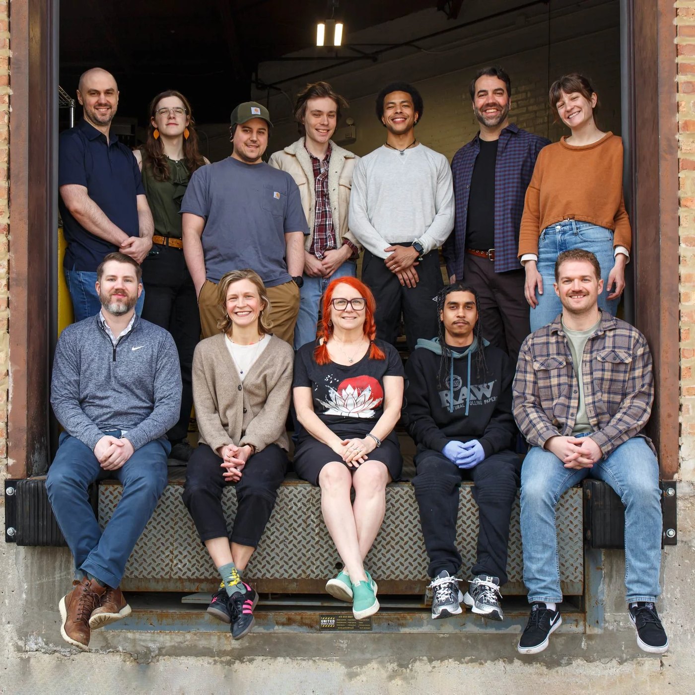 The KOBO team, twelve people, sitting and standing on the loading dock of the Chicago studio